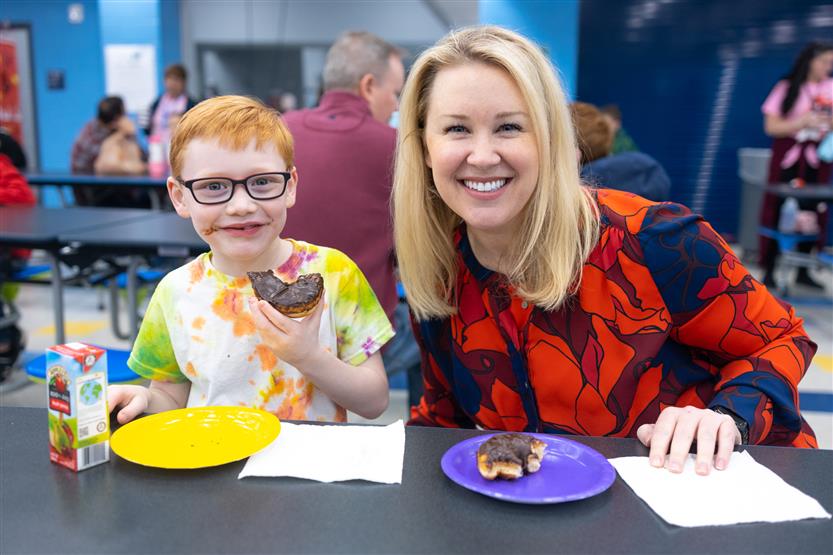 Creekside Elementary students eat donuts with a grown-up